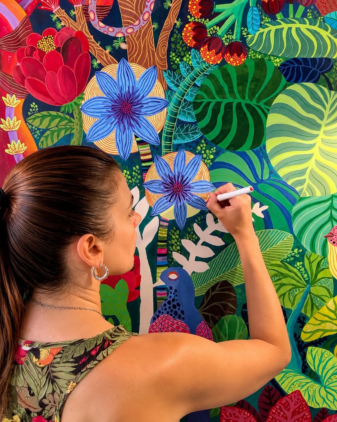 Coty Borio pintando un mural de flora y fauna